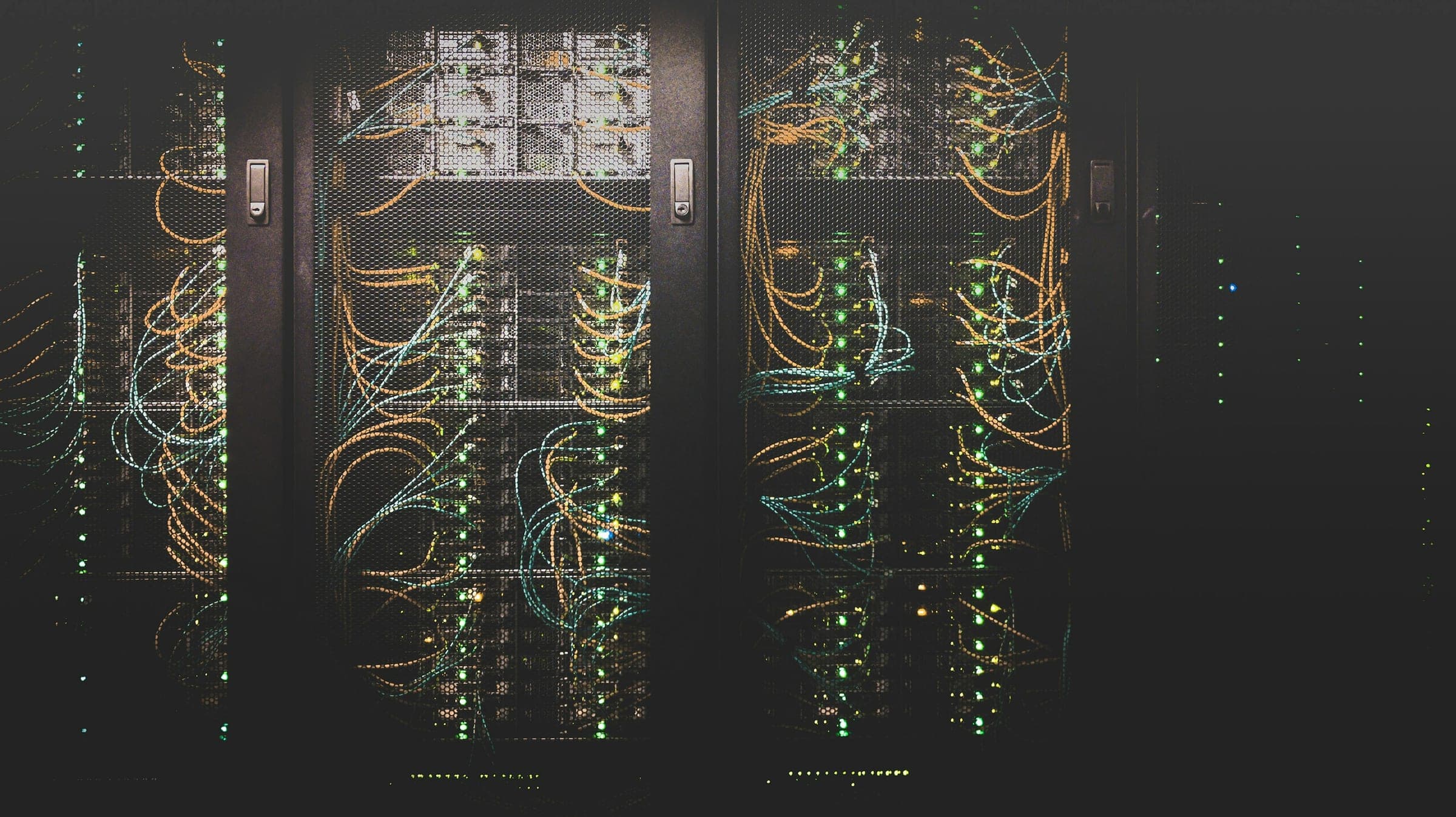 Server racks laced with amber and teal patch cabling